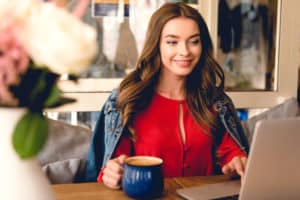 Beautiful woman wearing a red sweatshirt at a coffee shop making money with online surveys