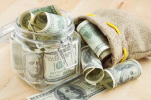 Dave Ramsey Baby Steps, dollar banknote in glass jar and bag of money