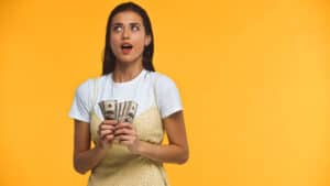 weird ways to make money woman holding a bunch of money with a shocked look