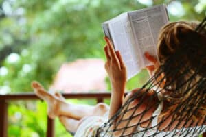 Get Paid To Read Books Young woman reading a book lying in a hammock