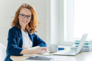 How To Become A Ghostwriter, Woman smiling while working on her writing skills