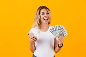 Watch Ads For Money Photo of pretty woman in basic clothing holding fan of dollar money isolated over yellow background