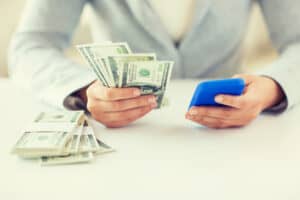 InboxDollars review featuring a person holding money at a table.