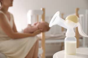 selling breast milk Mother and little baby indoors, focus on table with breast pump