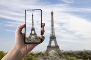get paid to take pictures Tourist taking photo of Eiffel tower in Paris, France. Man holding phone and taking picture.