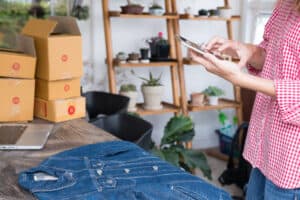 sites like craigslist young start up small business owner holding mobile phone and take photo of her product. freelance woman entrepreneur SME seller use smart phone to take picture and sell cloth on website. Online selling, internet marketing, e-commerce concept