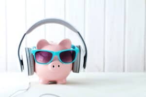 get paid to listen to music Headphones on piggybank on white wooden table