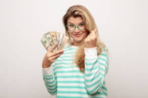 Jobs That Pay $30 An Hour young latin pretty woman against flat wall with dollar banknotes