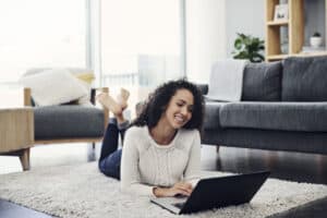 Online Jobs That Pay Daily Full length shot of an attractive young woman using a laptop while lying on the floor in her living room