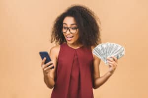 Woman smiling while holding money and phone, Shopkick Review