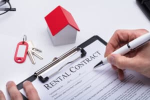 How Much Can I Rent My House For Human Hand Filling Rental Contract Form With House Model And Key On Desk