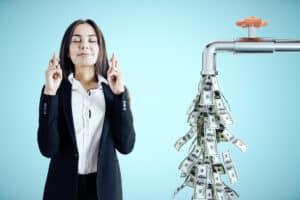Passive Side Hustles Businesswoman crossed her fingers for luck and water tap dripping dollar bills on blue background. Business and financial success concept